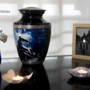 A black urn for ashes with a motorcycle driving to the sea with silver decorations