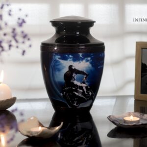 A black urn for ashes with a motorcycle driving to the sea with Black decorations