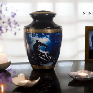 A black urn for ashes with a motorcycle driving to the sea with gold decorations